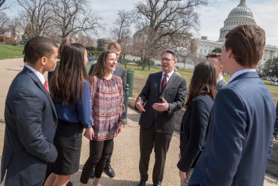 With the U.S. Capitol dome rising in the background, Virginia Tech President Tim Sands (at center) talks with eight student interns.